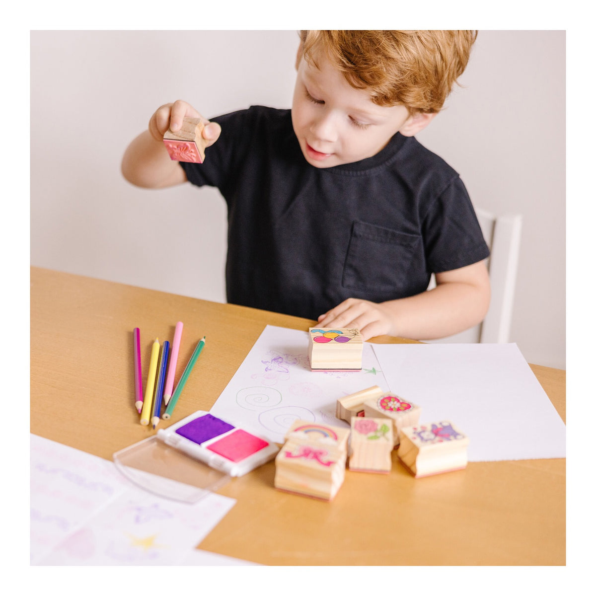 Child choosing a friendship stamp beside pencils, paper and the ink pad