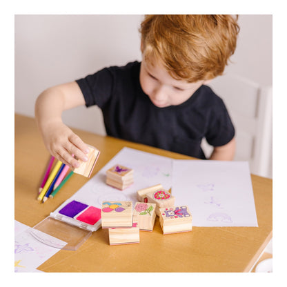 Child creating pictures with wooden friendship stamps and a two-colour ink pad