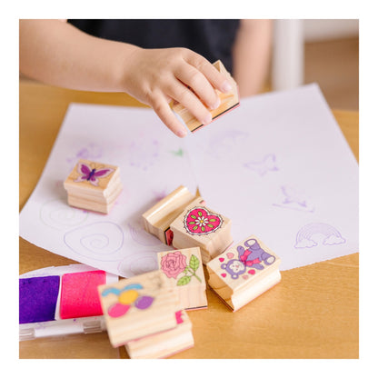 Child stamping friendship designs onto paper beside the open ink pad
