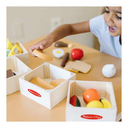 Child sorting wooden play food into the four storage crates