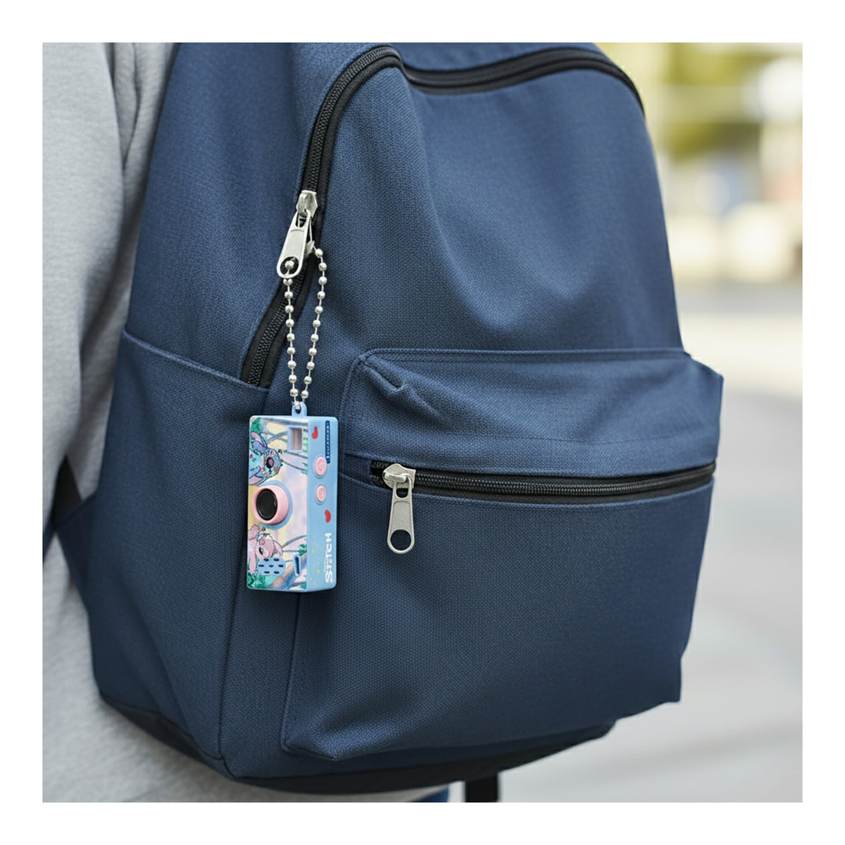 Disney Stitch mini keychain camera attached to a blue backpack