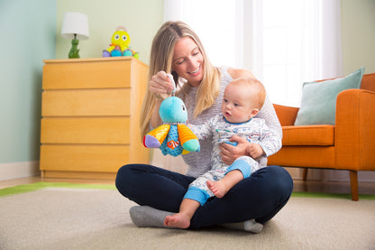 Parent holding Salty Sam clip-on octopus toy while seated with baby
