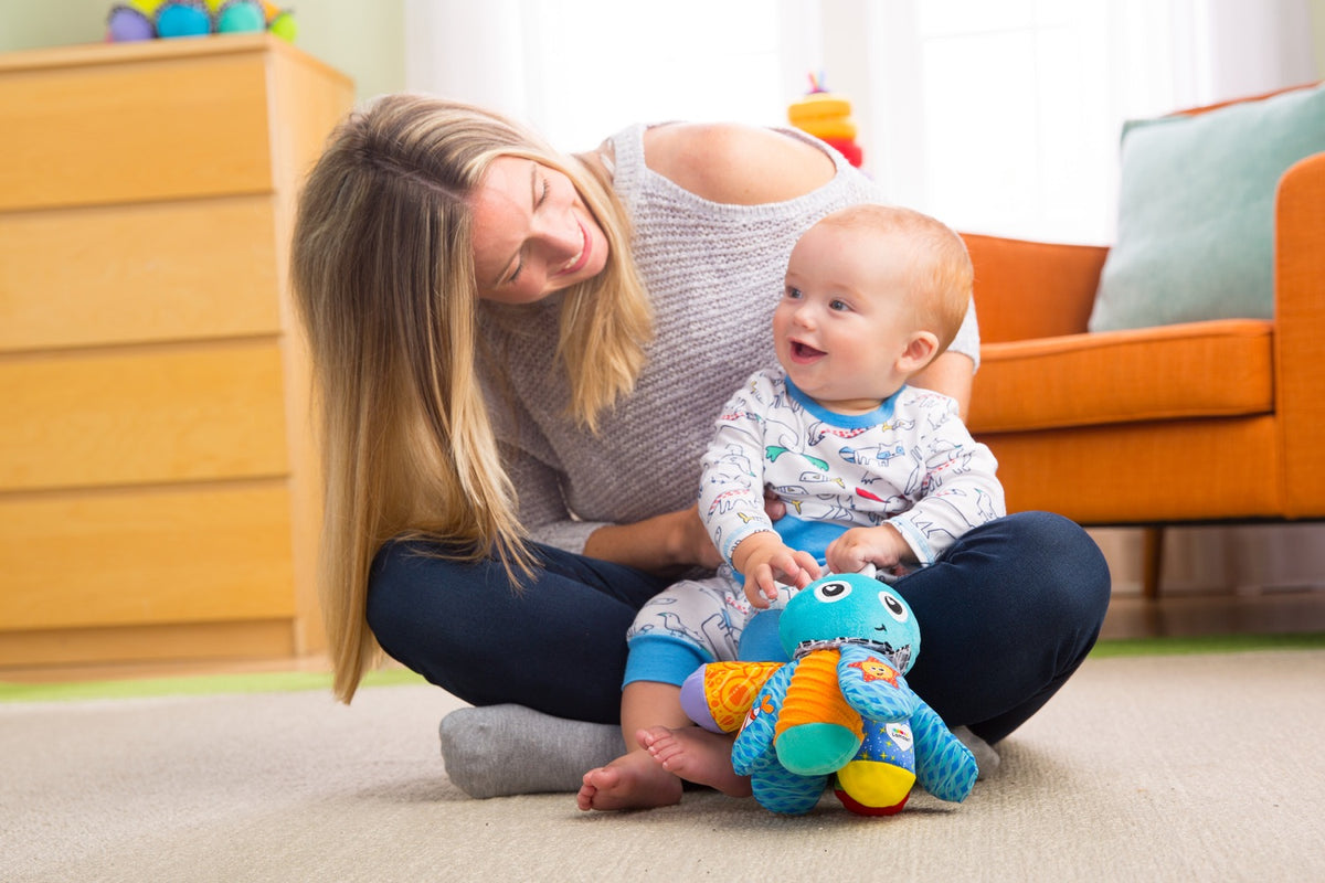 Baby playing with Salty Sam octopus toy while seated with a parent