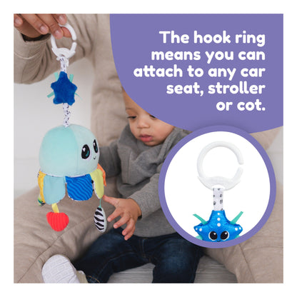Salty Sam stroller toy attached by its hook ring beside a baby