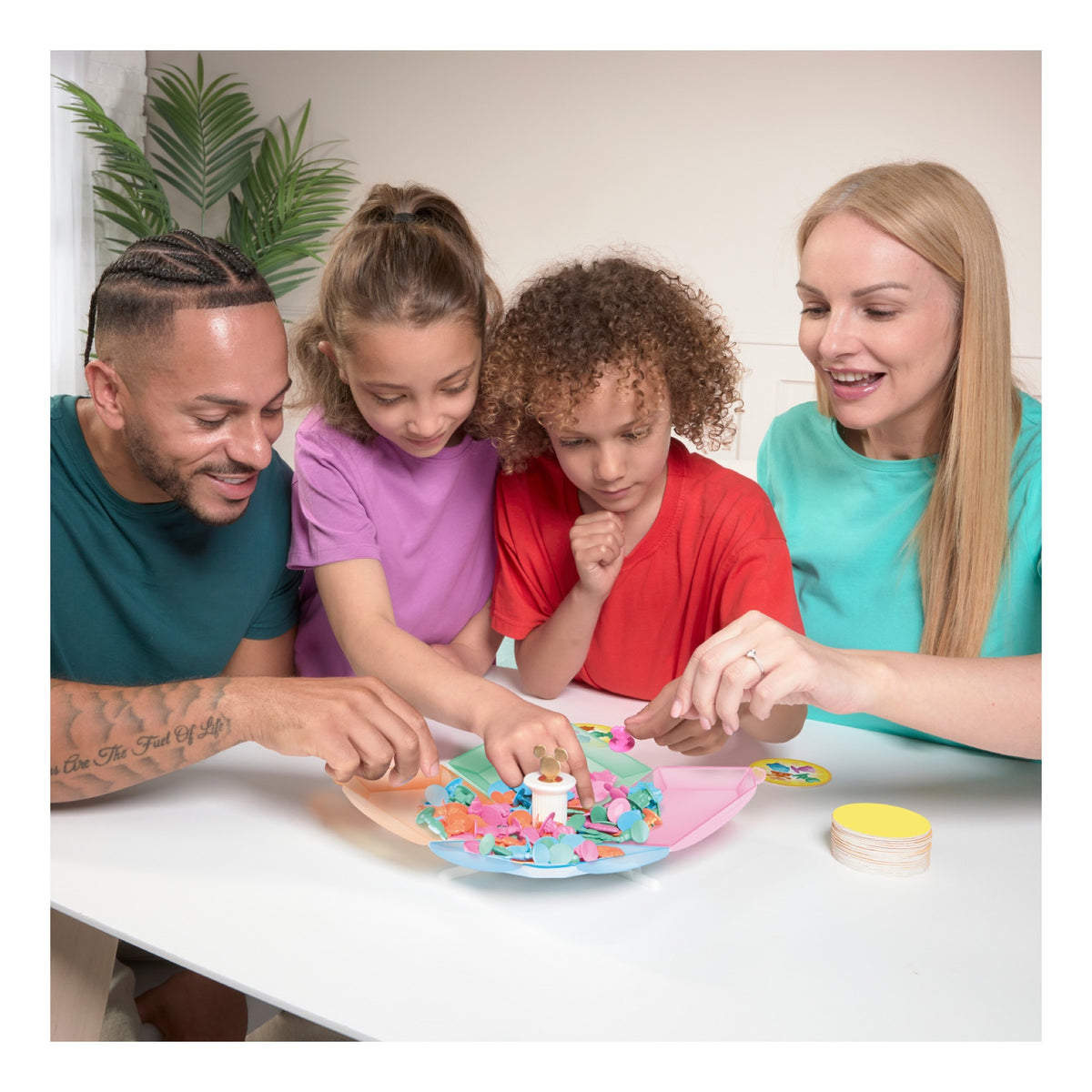 Family gathered around a table playing All 4 Won! Disney Edition